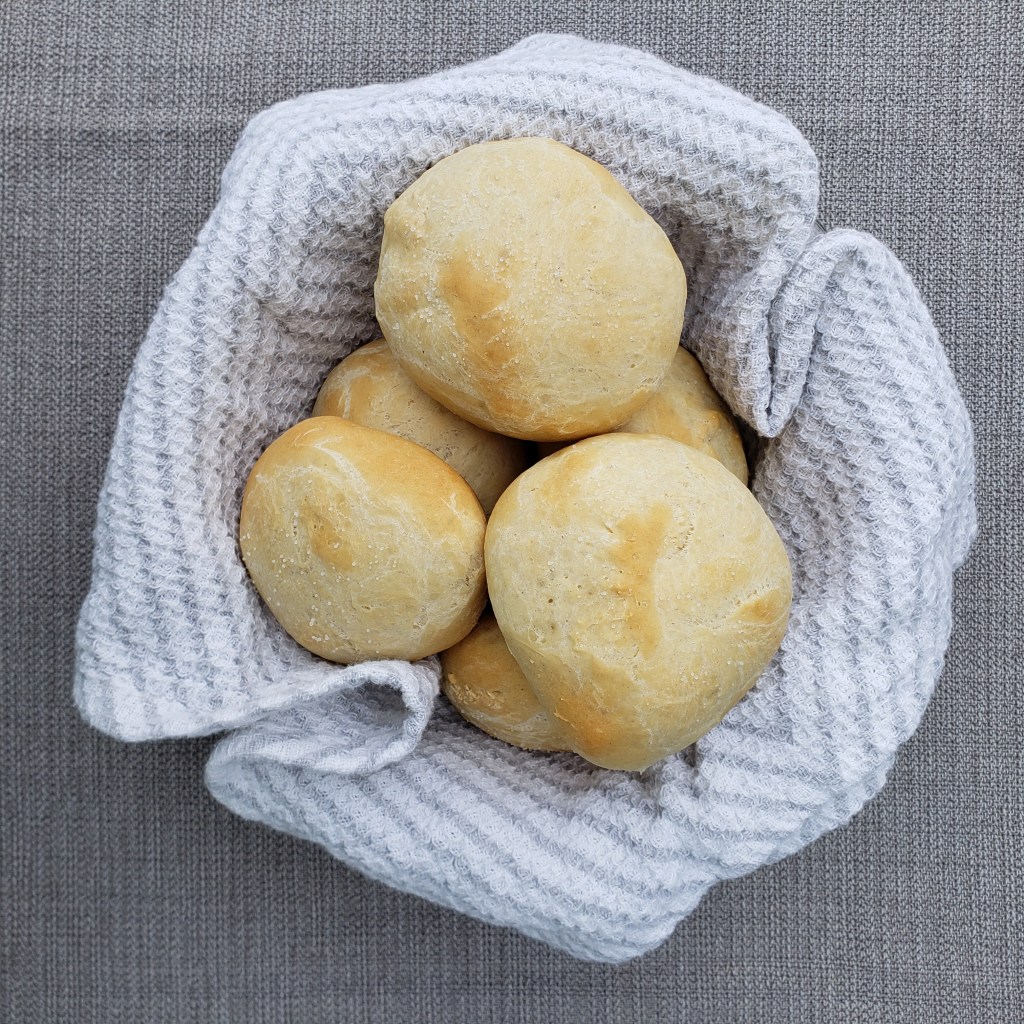 crusty rolls in bowl wrapped in white and gray stripped towel