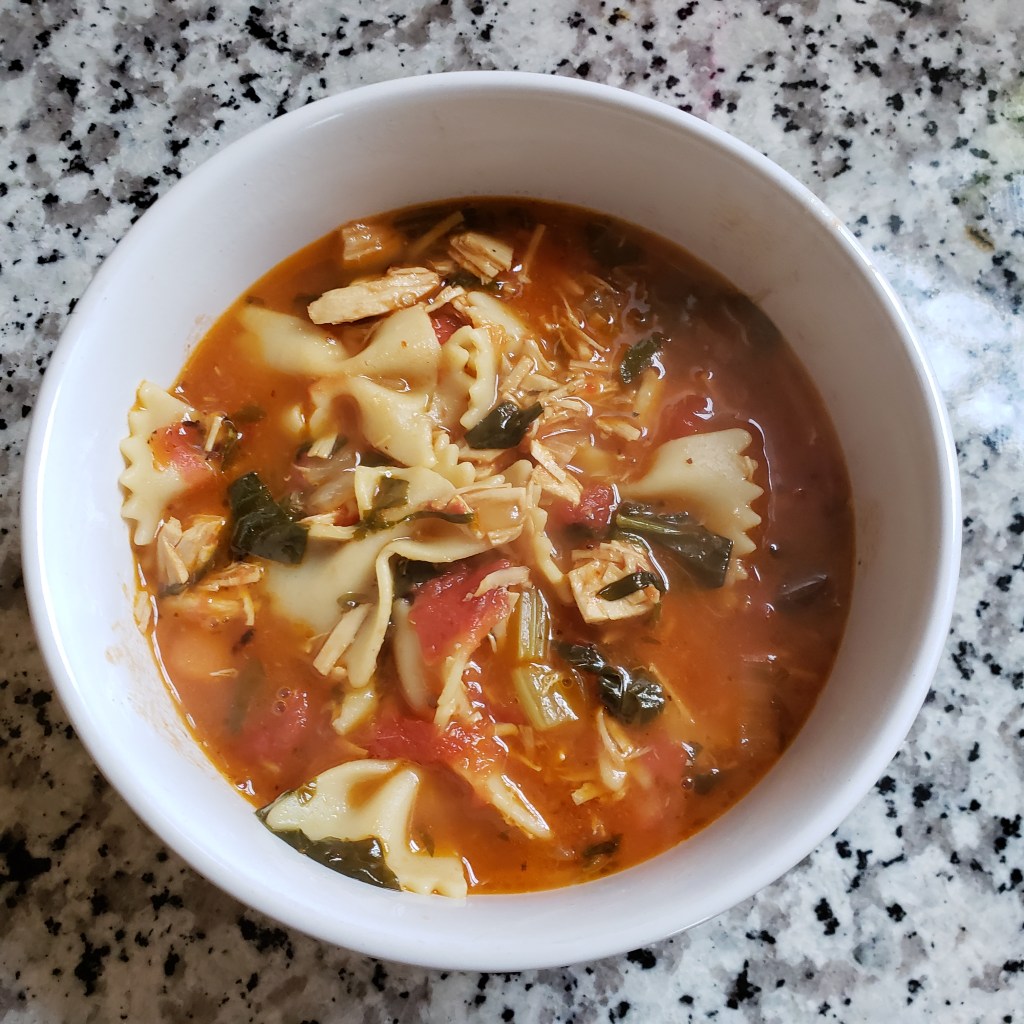 a bowl of Turkey soup with bowt ie pasta and vegetables 