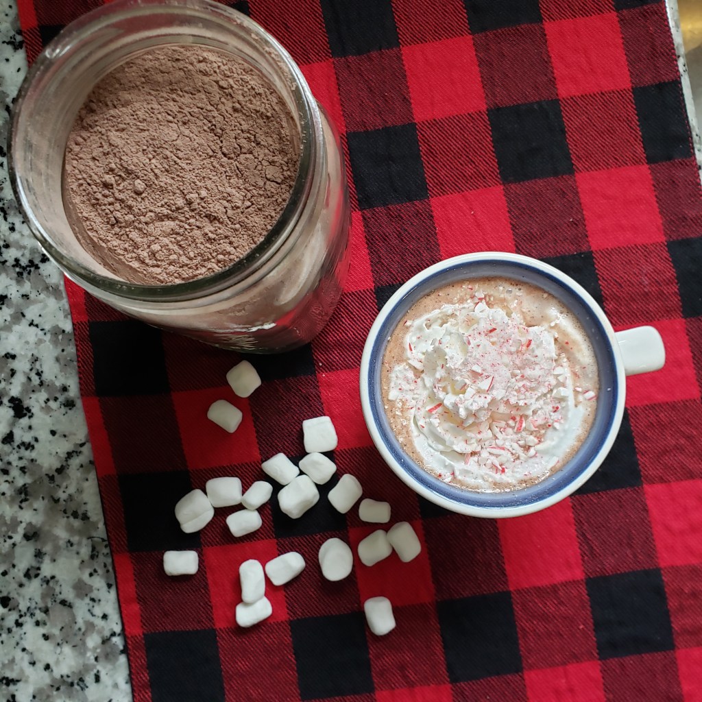 Cup of hot chocolate and jar of mix with mini marshmallows on the side